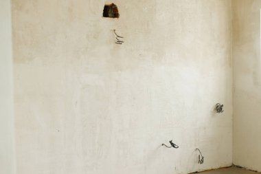 Elektrik kablolarının, alçı duvarların ve yeni binadaki toprağın olduğu bitmemiş bir oda. Ev ve ev yenileme konsepti. Ev geliştirme, kablolama
