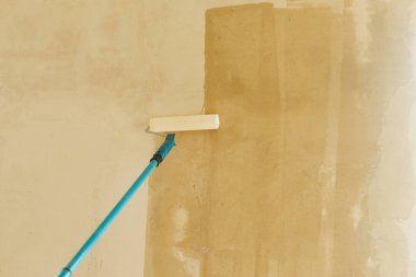 Yeni binadaki duvarları asma işlemi. Paten fırçası ve alçı kaplama duvarlar. Ev ve ev yenileme konsepti.