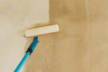 Yeni binadaki duvarları asma işlemi. Paten fırçası ve alçı kaplama duvarlar. Ev ve ev yenileme konsepti.