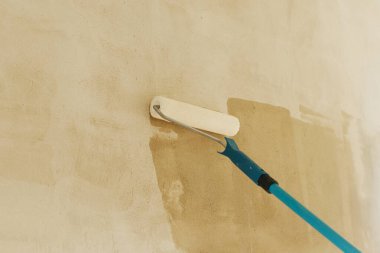 Yeni binada işçi duvarları astar. Paten fırçası ve alçı kaplama duvarlar. Ev ve ev yenileme konsepti.