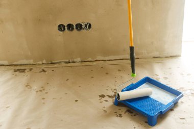 Paten fırçası ve tepsisi alçı duvarlar için yakın plan. Ev ve ev yenileme konsepti. Yeni binadaki duvarların hazırlanma süreci