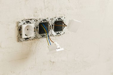 Prizi ve düğmesi olan elektrik kutusu. Alçılı duvara elektrik konnektörü yerleştiriliyor. Ev ve ev yenileme konsepti. Kablo