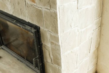 Tamamlanmamış oturma odasında şömine kapanıyor. Ev yenileme konsepti. Şömineyi doğal taş ve ahşap şömine ile süslüyor..