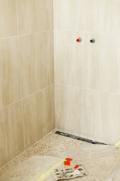 壁にトラバーチンタイルの水パイプと未完成のバスルームの床に排水シャワー 住宅や住宅改修の概念の建設 配管パイプライン — ストック写真