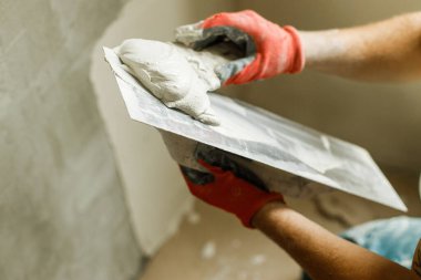 Alçı taşı ve spatulayla duvarları sıvayan bir işçi. Ev ve ev yenileme konsepti. # Yaklaş sıva ve becerikli ellerin malayla #