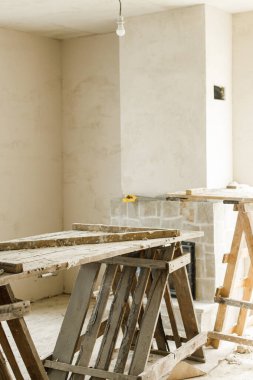 Ev ve ev yenileme konsepti. Ahşap merdiveni, şöminesi, alçı duvarları ve yeni binası olan bitmemiş bir oturma odası. Ev geliştirme