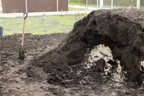 stock image Black soil pile and showel in backyard. Landscaping yard and garden work concept. Clean soil for cultivation and gardening