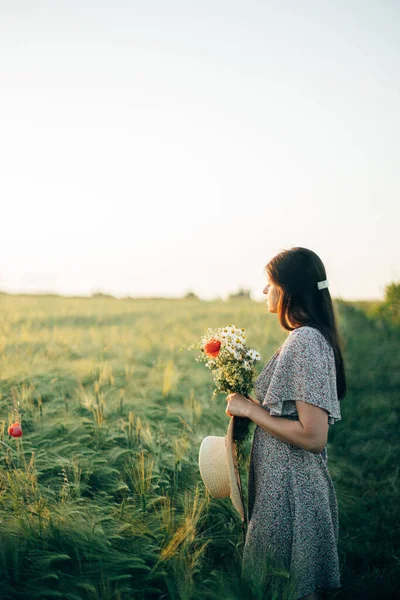 Arpa Tarlasında Günbatımının Tadını Çıkaran Kır Çiçekleriyle Güzel Bir Kadın — Stok fotoğraf