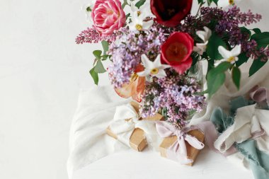 Anneler Günün kutlu olsun. Bahar leylağı, lale, nergis modern kırsal odada şimdiki ve pastel kurdelelerle düzenlenir. Kırsal ahşap masa üzerinde hediye kutusu olan şık bir buket. Mutlu Kadın Günleri