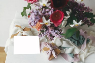 Anneler Günün kutlu olsun. Tebrik kartı, modern köy odasındaki ahşap masada hediye paketi ve pastel kurdelelerle süslü ve şık bir buket. Mesaj için yer var. Mutlu Kadın Günleri. Kartpostal modeli