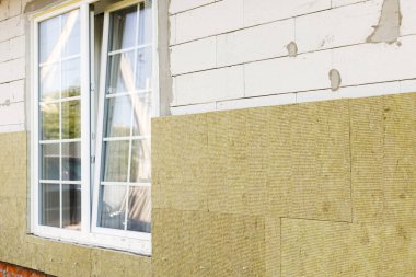 Ev yalıtımı konsepti. Mineral yünü, termal gelişim ve enerji tasarrufu ile yalıtım malzemesi. Modern çiftlik evinin yenilenmesi, taştan yün panellerle kaplanıyor.