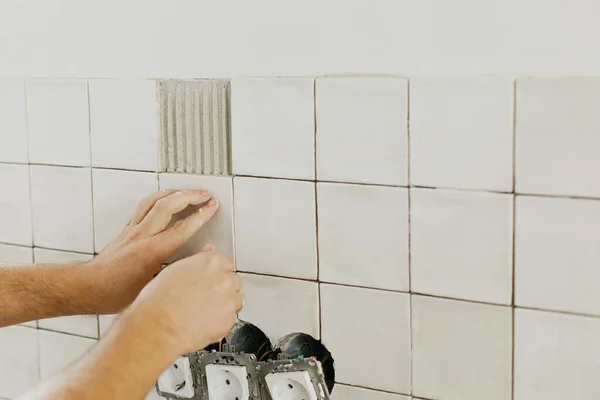 接着剤を閉じる上で近代的な正方形のタイルを敷設手 石膏壁にスタイリッシュな白いタイルをインストールする作業者 — ストック写真