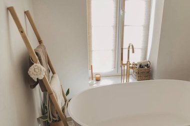 Şık bir banyo tasarımı. Zeminden altın musluğu olan modern küvet, havluklu ahşap merdiven ve büyük pencere, modern ekolojik banyo iç mimarisi..