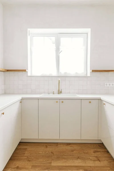 现代最小厨房设计 时尚的白色厨房橱柜 装有黄铜把手 水龙头和窗户水槽 以及新的丑闻中的木制架子 现代厨房内部 — 图库照片