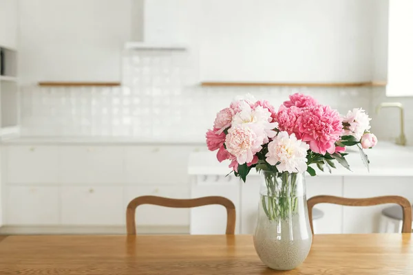 新しい家の島 木製の棚や家電製品とスタイリッシュな白いキッチンを背景に木製のテーブルの上に花瓶の美しい牡丹 農家のモダンなキッチンインテリア — ストック写真
