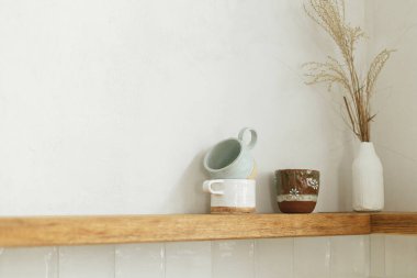 Yeni İskandinav evindeki modern mutfağın arka planında mutfak aletleri, fincanları ve dekorları olan ahşap bir raf. Modern mutfak iç mimarisi ve şık aksesuarlar.