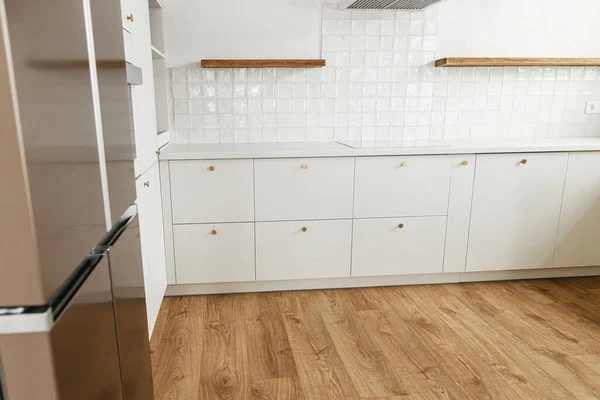 现代最小厨房设计 时尚的白色厨房橱柜 有黄铜把手 木制架子和新丑闻中的家用电器 现代厨房内部 — 图库照片