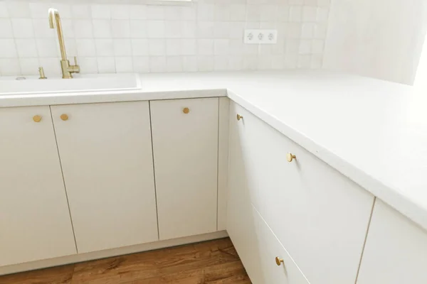 现代厨房的内部 时尚的白色厨房橱柜 配有黄铜水龙头和旋钮 花岗岩岛和新丑闻中的家用电器 现代最低厨房设计 — 图库照片