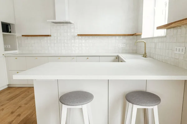 现代最小厨房设计 时尚的白色厨房橱柜 配有黄铜把手 水龙头 花岗岩岛 木制货架和新丑闻中的家用电器 现代厨房内部 — 图库照片