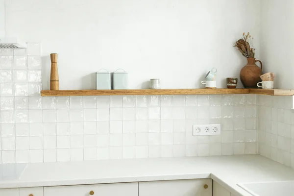 现代厨房的内部 时尚的白色厨房橱柜 配有黄铜把手和花岗岩工作台 木制架子上有器皿和装饰在新的丑闻鸟的房子 现代最低厨房设计 — 图库照片