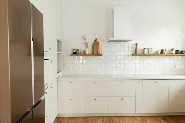现代厨房的内部 时尚的白色厨房橱柜与黄铜把手 木制架子与器具和器具在新的丑闻鸟的房子 现代最低厨房设计 — 图库照片