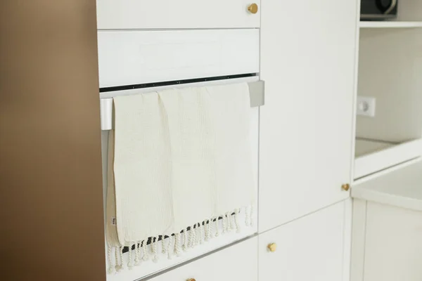 时尚的白色厨房橱柜与黄铜旋钮 电炉与毛巾和器具在新的丑闻鸟屋 现代最小厨房设计 现代厨房内部 — 图库照片
