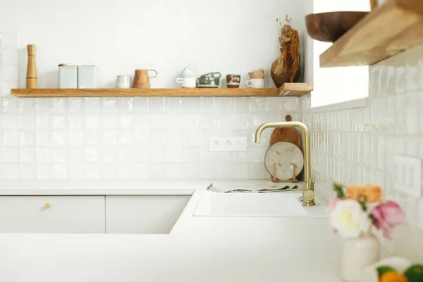 现代的白色厨房 有黄铜水龙头 花岗岩台面 木制架子上的器皿和玫瑰在新的丑闻鸟屋 现代厨房的内部 现代最低厨房设计 — 图库照片