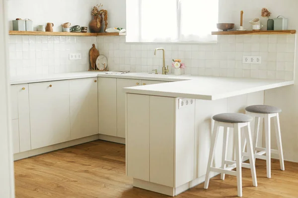 现代厨房的内部 在新的丑闻中 风格别致的白色厨房橱柜 装有黄铜把手 花岗岩岛 木制架子上的器具和器皿 现代最低厨房设计 — 图库照片