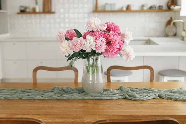 新しい素朴な農家の家電製品とスタイリッシュな白いキッチンを背景に木製のテーブルの上に花瓶に美しい牡丹 モダンなキッチンインテリア 最小限のキッチンデザイン — ストック写真