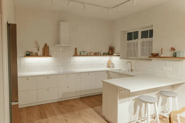 现代厨房的内部 时尚的白色厨房橱柜与黄铜旋钮 花岗岩岛 电器和灯在新的丑闻鸟屋 现代最低厨房设计 — 图库照片