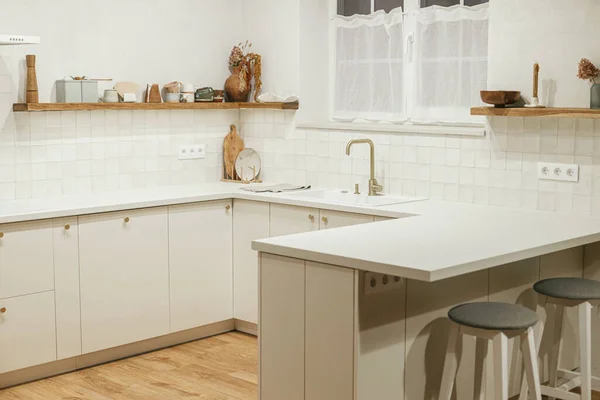 现代厨房的内部 新屋的时尚白色厨房橱柜 装有黄铜把手 花岗岩岛 家用电器和夜灯 现代最低厨房设计 — 图库照片