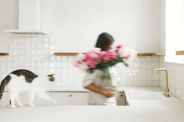 Размытая Женщина Своей Кошкой Расставляющей Пионы Вазе Фоне Минимальной Белой — стоковое фото