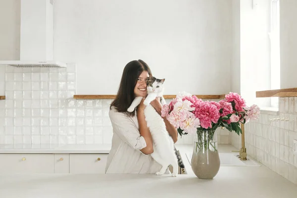 Счастливая Женщина Обнимает Милую Кошку Пионы Вазе Фоне Минимальной Белой — стоковое фото