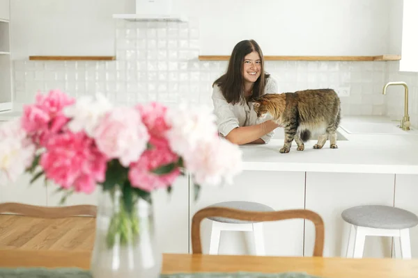 Щаслива Жінка Пестить Милий Кіт Тлі Мінімально Білої Кухні Букетом — стокове фото
