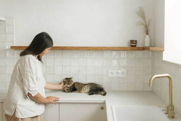 Κομψή Γυναίκα Χαϊδεύει Γάτα Της Μια Νέα Μίνιμαλ Λευκή Κουζίνα — Φωτογραφία Αρχείου