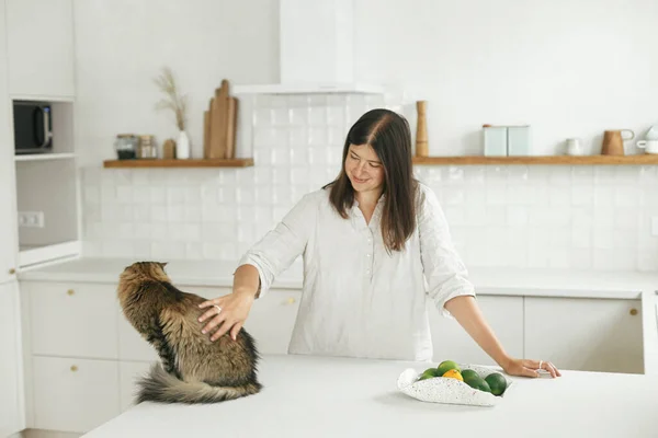 Κομψή Γυναίκα Χαϊδεύει Γάτα Της Μια Νέα Μίνιμαλ Λευκή Κουζίνα — Φωτογραφία Αρχείου