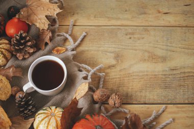 Warm cup of tea, pumpkins, fall leaves, cozy scarf on rustic wooden table flat lay with space for text. Hygge autumn template. Happy Thanksgiving. Fall still life banner