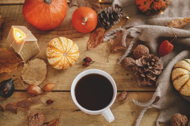 Autumn flat lay. Warm cup of tea, pumpkins, fall leaves, candle, cozy scarf on rustic wooden table. Hygge autumn banner. Happy Thanksgiving. Fall still life