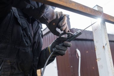 Kalkanlı metal kaynaklama. Elektrotlarla metal kaynak yapan, koruyucu kask ve eldiven takan bir işçi. Elektro kaynak ve elektrik kıvılcımlarını kapat