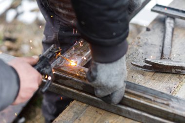 Kalkanlı metal kaynaklama. Elektrotlarla metal kaynak yapan, koruyucu kask ve eldiven takan bir işçi. Elektro kaynak ve elektrik kıvılcımlarını kapat