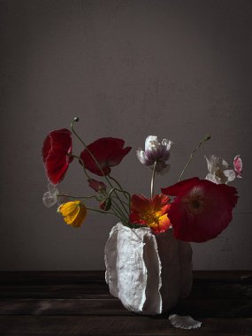 Huysuz kırsal arka planda güneş ışığında vazoda güzel gelincikler. Şık çiçekler natürmort, sanatsal kompozisyon. Çiçek dikey duvar kağıdı