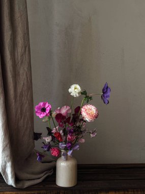 Çiçekler hala hayat. Kasvetli kırsal arka planda vazodaki güzel çiçekler. Lathyrus, anemone ve ranunculus 'un sanatsal kompozisyonu. Çiçek dikey duvar kağıdı