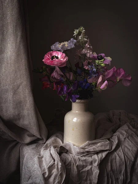 Çiçekler hala hayat. Huysuz arka planda vazoda güzel renkli çiçekler. Latirus, anemon, ranunculus ve Delphinium 'un sanatsal kompozisyonu. İnanılmaz dikey çiçek duvar kağıdı.