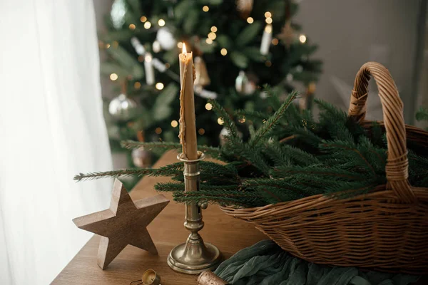 メリークリスマスとハッピークリスマス スカンジナビアの部屋の祝祭の装飾されたクリスマス ツリーに対するテーブルの火の枝 ヴィンテージのろうそくおよび木星が付いているスタイリッシュな素朴なバスケット — ストック写真