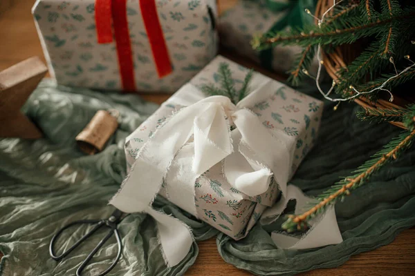 スタイリッシュな包まれたクリスマスの贈り物 お祝いの装飾されたスカンジナビアの部屋のテーブルに火の枝が付いている素朴なバスケット 大気のイメージ メリークリスマス — ストック写真
