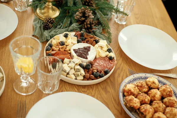 クリスマスツリー ブランチ 松コーン キャンドル メガネ カトラリーとしてクランベリーソースを用いたモダンなクリスマスチーズプレッター 休日のための食事の取り決め クリスマステーブルの設定 — ストック写真