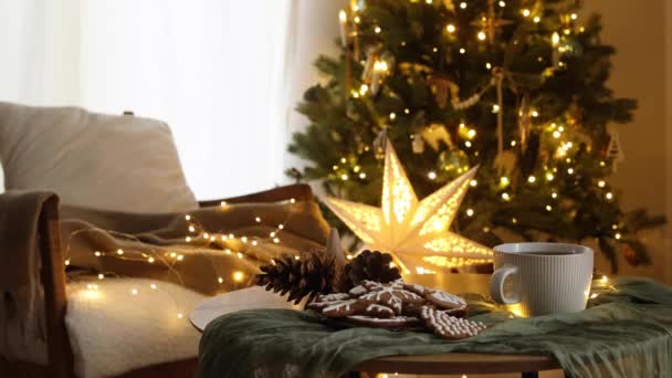 手穿舒适的毛衣 把时尚包装的礼物放在现代椅子上 背景是喜庆的圣诞树 房间里点着灯 大气圣诞前夕的镜头 圣诞快乐 — 图库视频影像