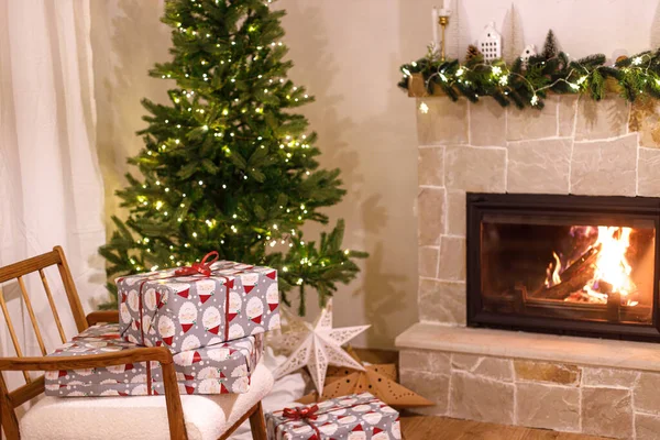 时尚的圣诞礼物包在扶手椅上 靠着圣诞树 点着喜庆的灯和舒适的壁炉 圣诞前夕 放假时间 有圣诞礼物的大气客厅 — 图库照片