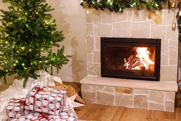 スタイリッシュな包まれたクリスマスギフト お祝いのライトと居心地の良い燃える暖炉付きのクリスマスツリー 大気圏のクリスマスイブ 休日の時間 メリークリスマス — ストック写真