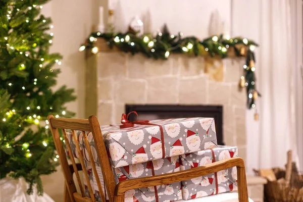 メリークリスマス お祝いのライトと居心地の良い暖炉でクリスマスツリーに対する腕の椅子にスタイリッシュな包まれたクリスマスギフト 大気のクリスマスイブ 休日の時間 — ストック写真